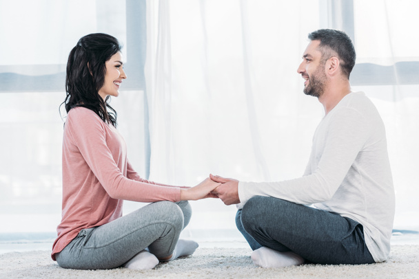 stock photo smiling man woman casual clothes sitting lotus pose meditating holding